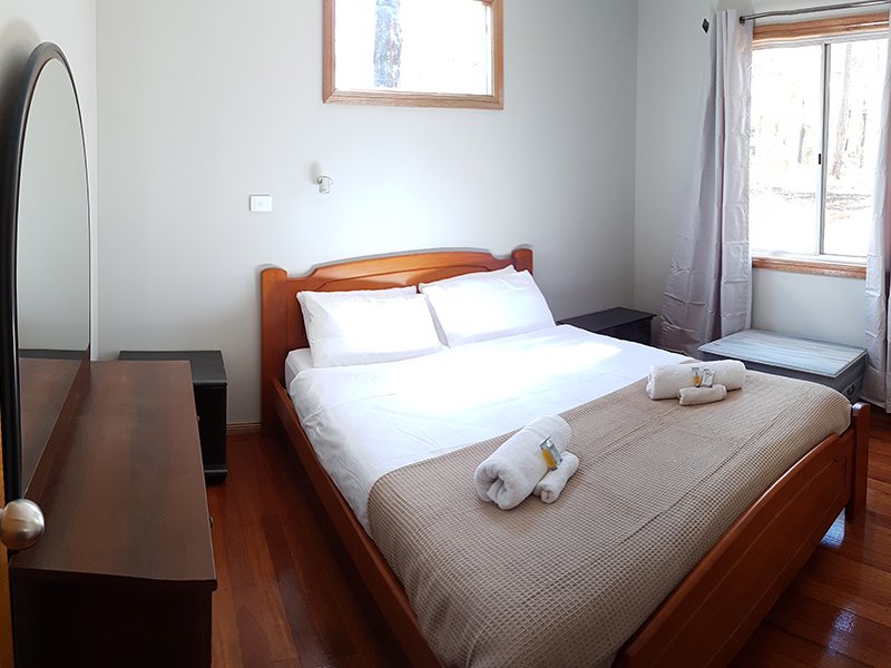 Rainforest cabin bedroom with queen bed and timber floors